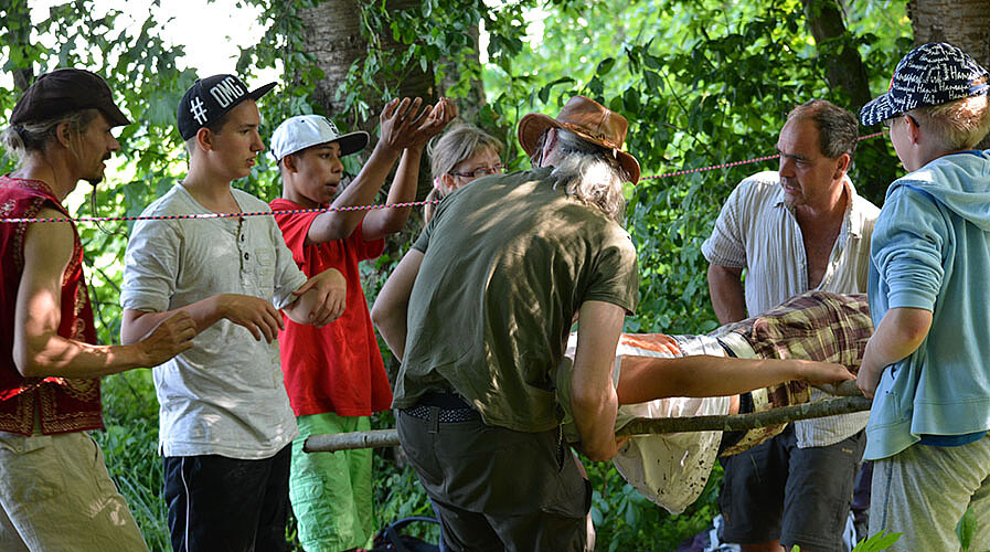Erlebnispädagogik Therapie findet auch in der Gruppe statt. Vertrauen lernen. Die Gruppe trägt eine liegende Person.