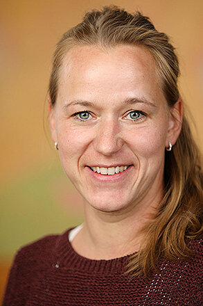 Binaka Bork nach links gewandt und freundlich lächelnd.